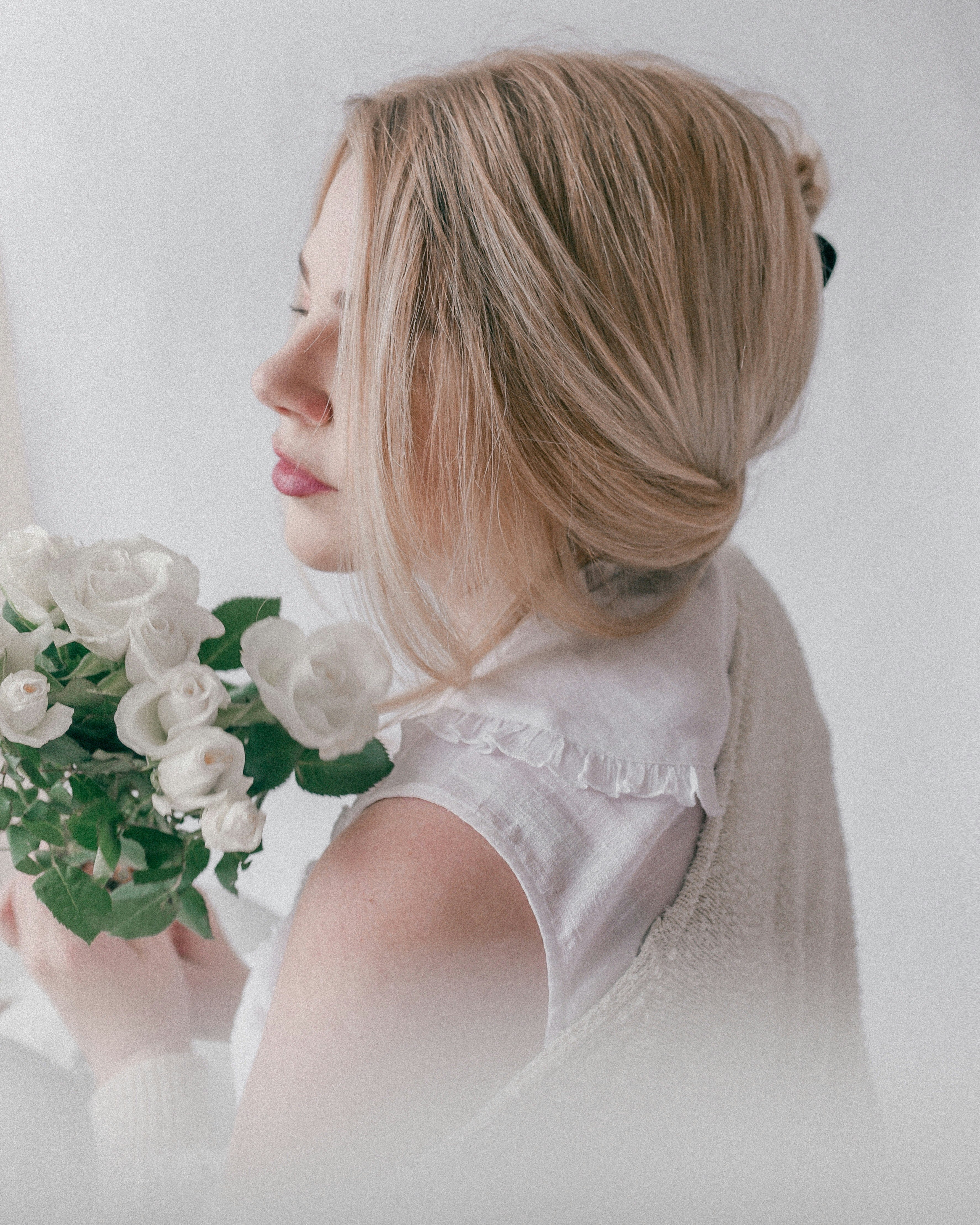 woman in white sleeveless dress holding white rose bouquet